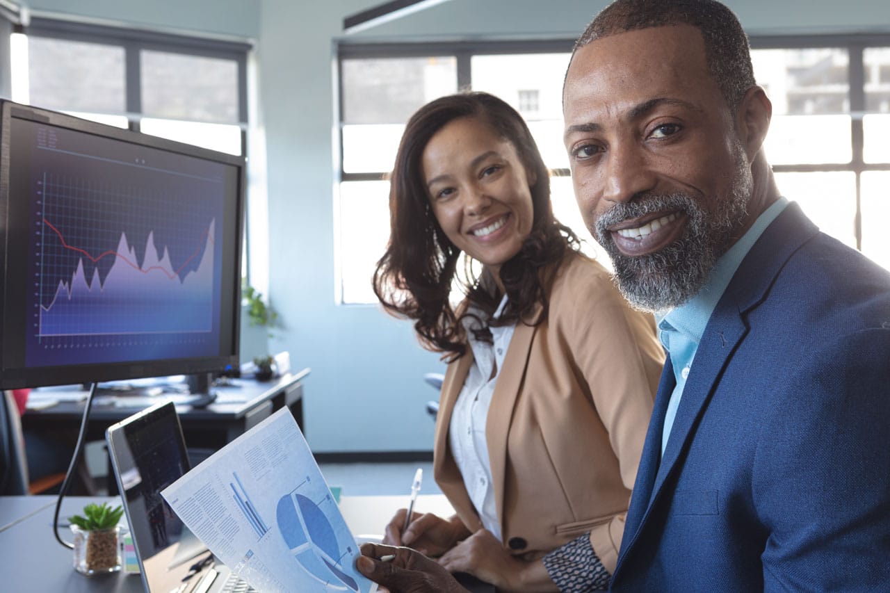 Two business professionals discussing financial health with graphs and charts in a modern office setting.