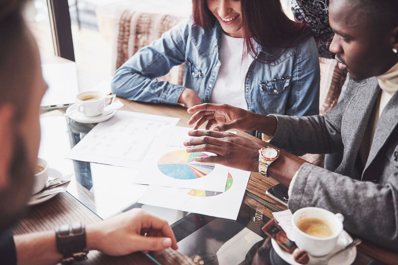 Entrepreneurs discussing diversification strategies with financial charts at a café.