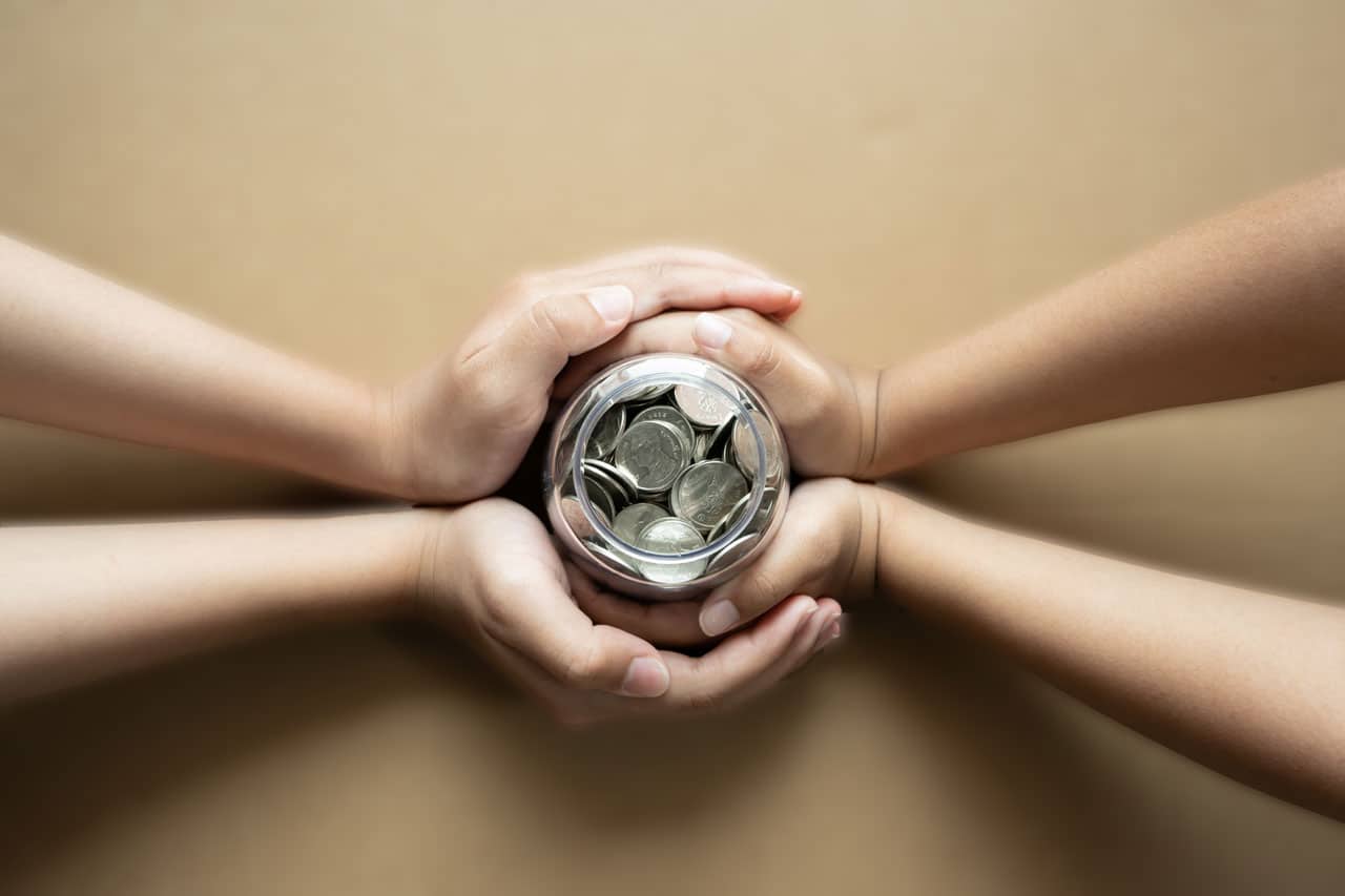Hands holding a jar of coins symbolizing stewardship and financial responsibility