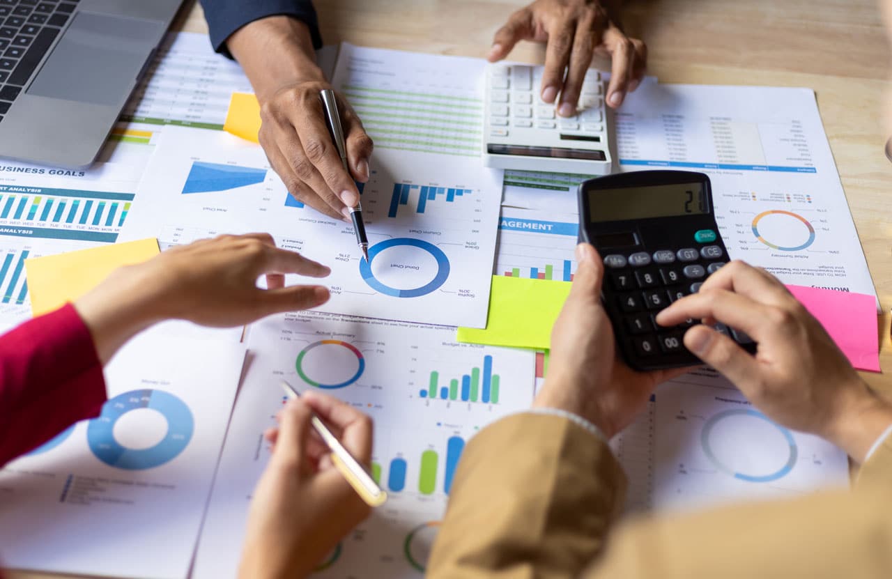 A professional team analyzing charts and calculators to update a business financial plan during a life shift.